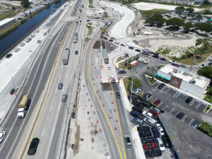 Aerial view of Frontage Rd and NW 95 St with temporary travel lanes and concrete pavement under construction. Nearby businesses such as Popeye's are visible.